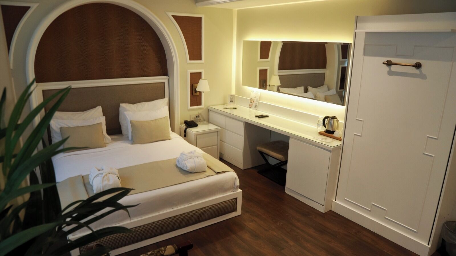 A hotel room with a bed, desk, and wardrobe.
