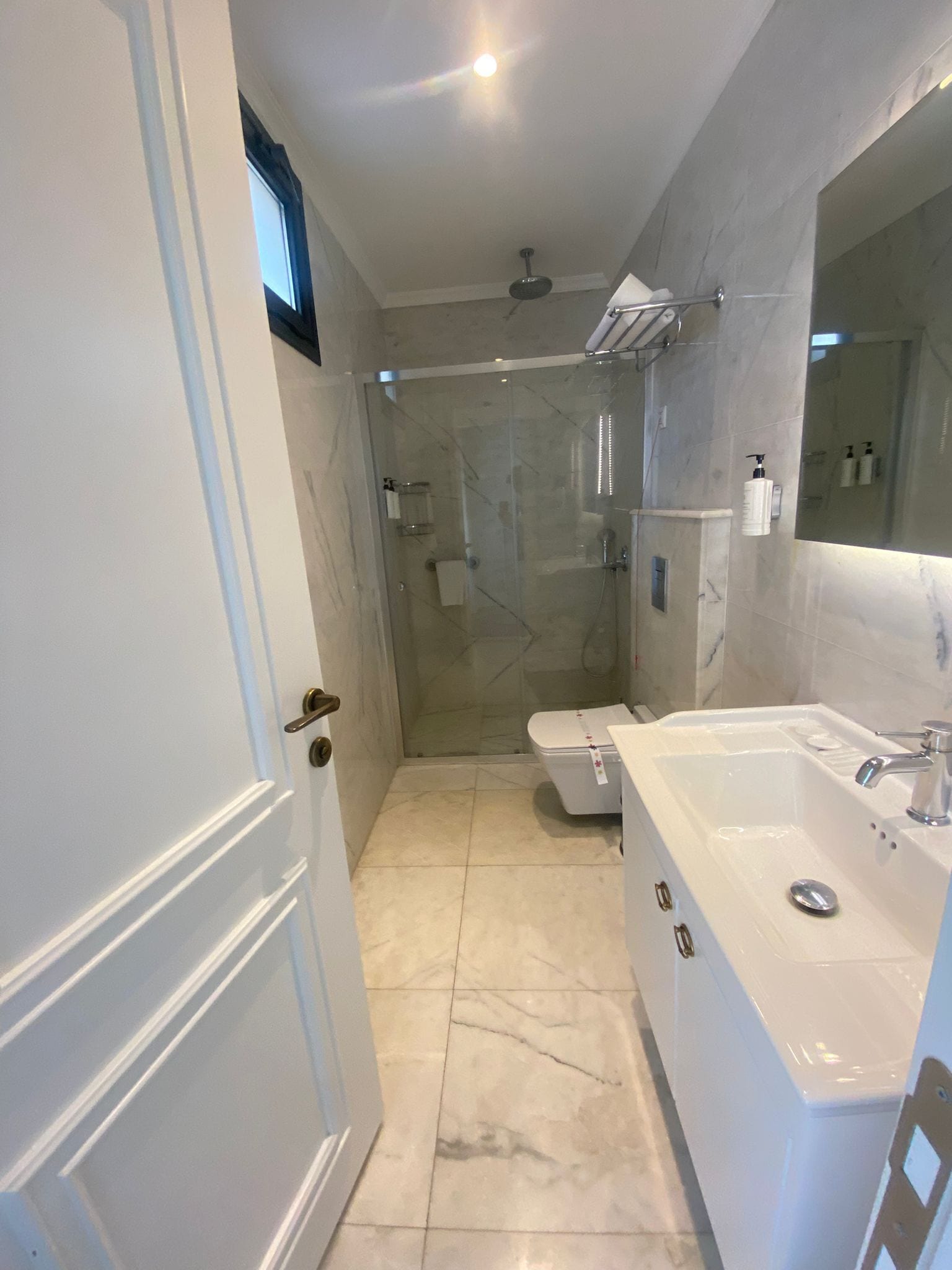 Un baño moderno con ducha envuelta en vidrio, una bañera blanca y un espejo grande.