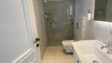 Un baño moderno con ducha envuelta en vidrio, una bañera blanca y un espejo grande.