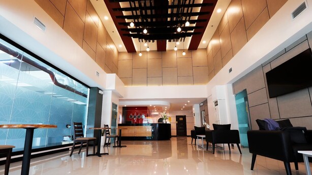 A modern hotel lobby with a reception desk, seating area, and a large glass wall. - Hotel Sogo Fairview  (Quezon City)