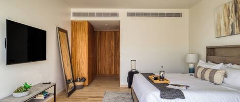 A modern hotel room with a bed, bedside table, TV, and a ceiling fan.