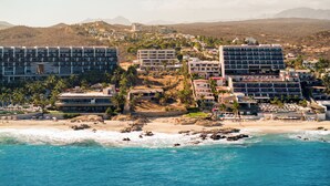 Une station balnéaire dotée de plusieurs bâtiments d’hôtel, d’une plage et d’un paysage montagneux en arrière-plan.