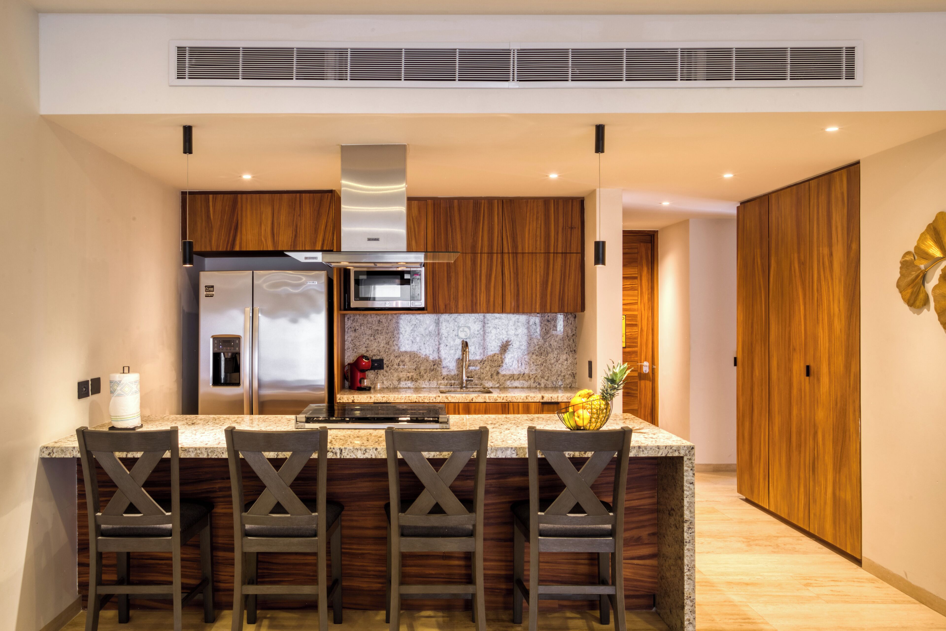 A modern kitchen with a central island, stainless steel appliances, wooden cabinetry, and a decorative wall piece.