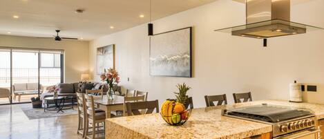 A modern kitchen with a granite countertop, a built-in stove, and a dining area with wooden chairs and a table.
