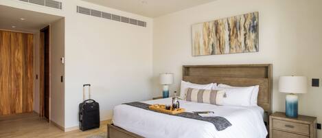 A hotel room with a bed, bedside tables, a ceiling fan, a wooden wardrobe, and a large abstract painting on the wall.