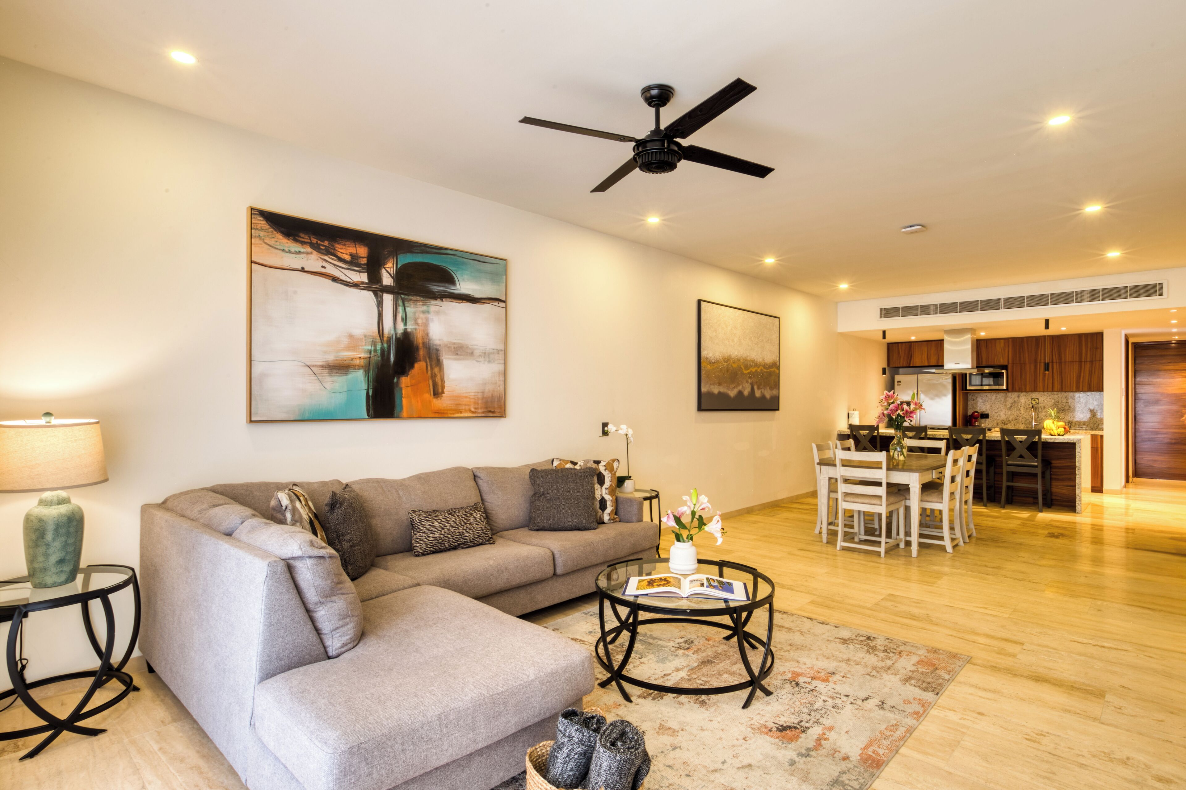 A modern living room with a grey sofa, a coffee table, and a dining area with a wooden table and chairs.
