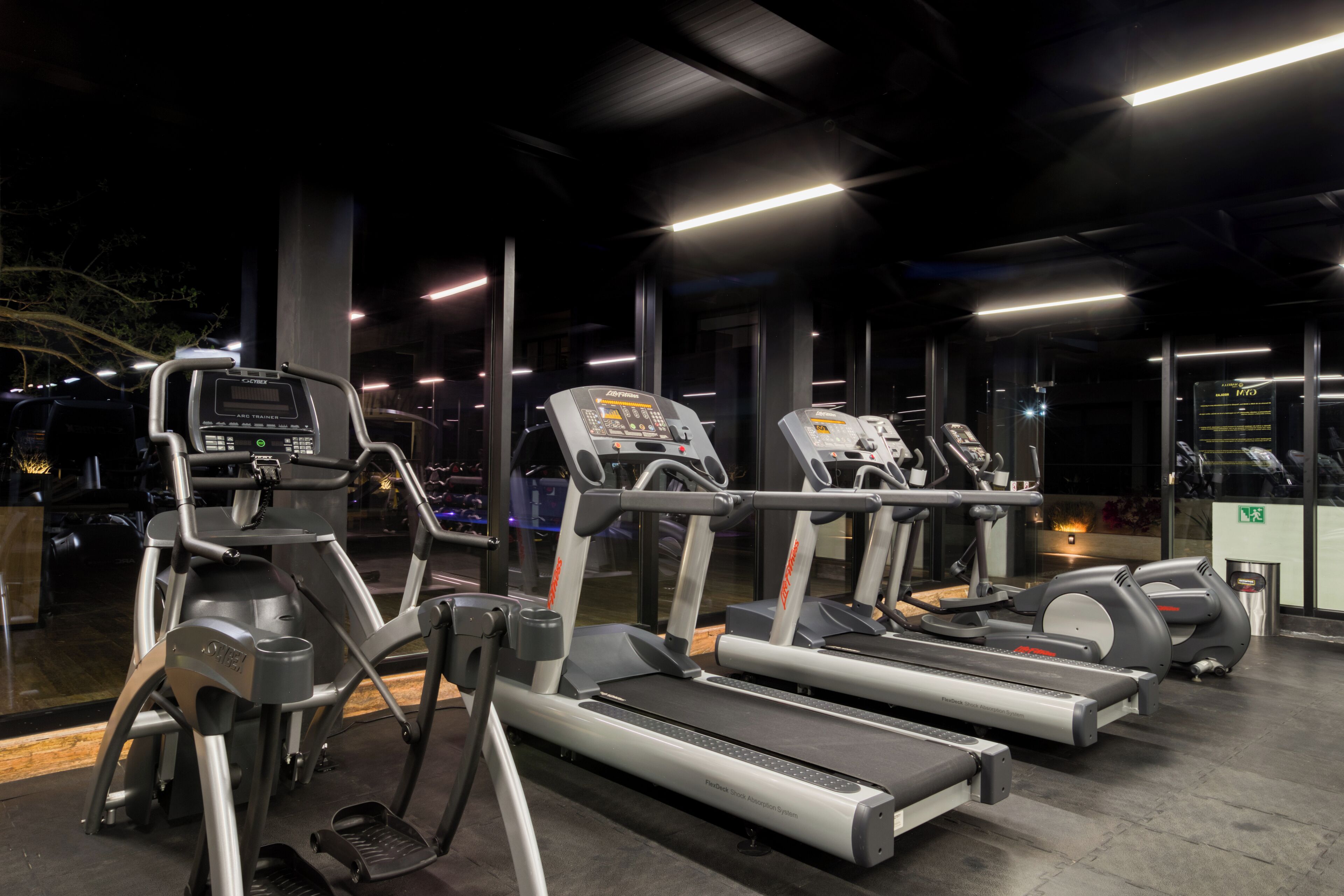 Un gimnasio equipado con cintas de correr, elípticas y una bicicleta estática.