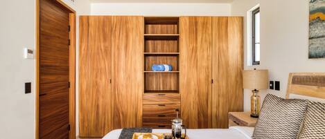 A bedroom with a wooden wardrobe, a bedside table with a lamp, a tray with breakfast, and an open book on the bed.