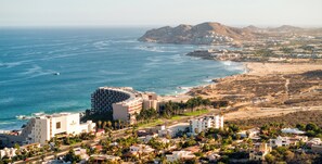 A coastal hotel with a curved building, beachfront view, and a desert landscape in the background. - Marella Cabo (Cabo San Lucas)