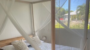 A bed with a canopy, pillows, and a view of the outside. - Villa Tropic ' AL (Saint-François)