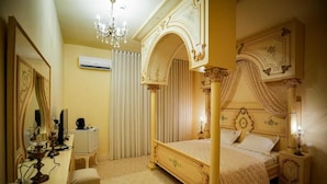 A four-poster bed with ornate detailing, a bedside table with a lamp, and a mirror with a draped curtain. - Gîte FEKI (Agareb)