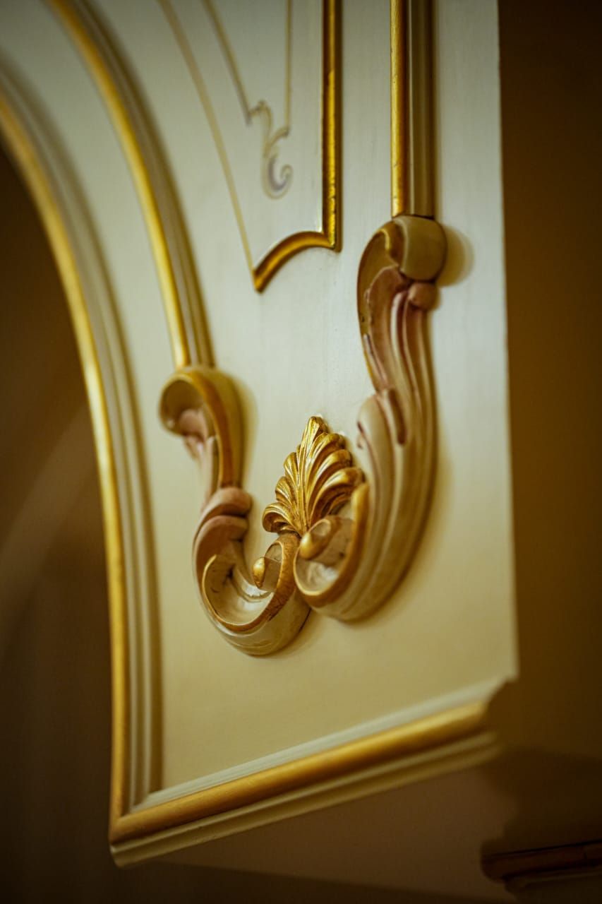 A detailed architectural feature with ornate gold and white decorations, likely part of a building's interior design.