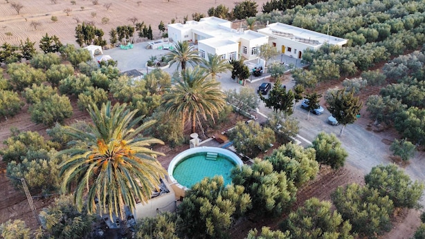 An aerial view of a resort with multiple buildings, a swimming pool, and surrounding vegetation. - Gîte FEKI (Agareb)
