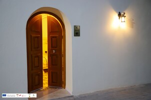 Un pasillo con una puerta de madera y una lámpara fijada a la pared.