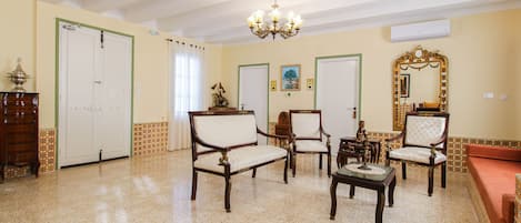 Un salón comedor amplio con una araña, varias sillas, un sofá y una mesa de centro.