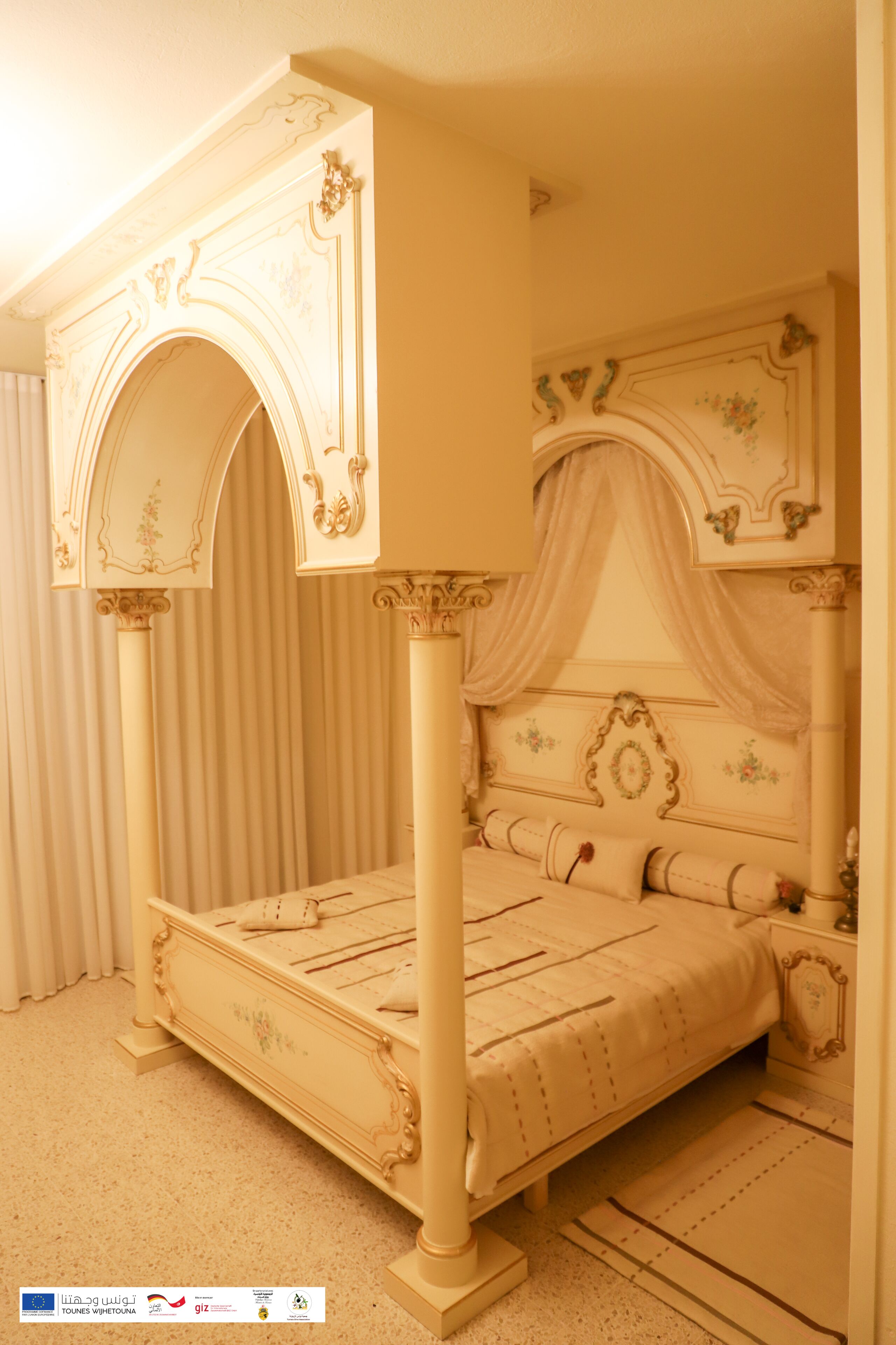 A four-poster bed with ornate carvings, a canopy, and a matching nightstand.