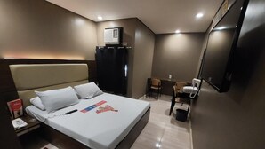 A modern hotel room with a large bed, a desk, a chair, a TV, and a minibar. - Hotel Sogo Timog 2 (Quezon City)