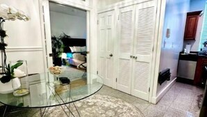 A dining area with a glass table, a hanging chair, and white louvered doors. - Accept daily stays NYC West Village Entire Place (New York)