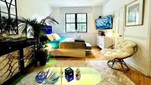 A bedroom with a bed, a TV, a chair, and a desk with a plant. - Accept daily stays NYC West Village Entire Place (New York)