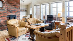 A cozy living room with leather sofas, a wooden coffee table, and a brick fireplace. - Amazing home in Midsund with WiFi (Midsund)