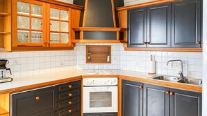 A kitchen with wooden cabinets, a built-in oven, a sink, and a coffee maker. - Amazing home in Midsund with WiFi (Midsund)