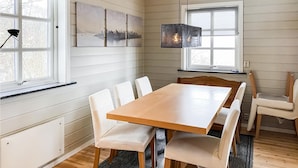 A dining area with a wooden table and white chairs, a cityscape painting on the wall, and a window with a view of trees. - Amazing home in Midsund with WiFi (Midsund)