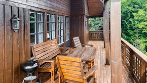 A wooden deck with a table and chairs, a barbecue grill, and a railing overlooking greenery. - Amazing home in Midsund with WiFi (Midsund)