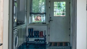 A laundry area with a washing machine, drying racks, and a small window with a view of greenery outside.