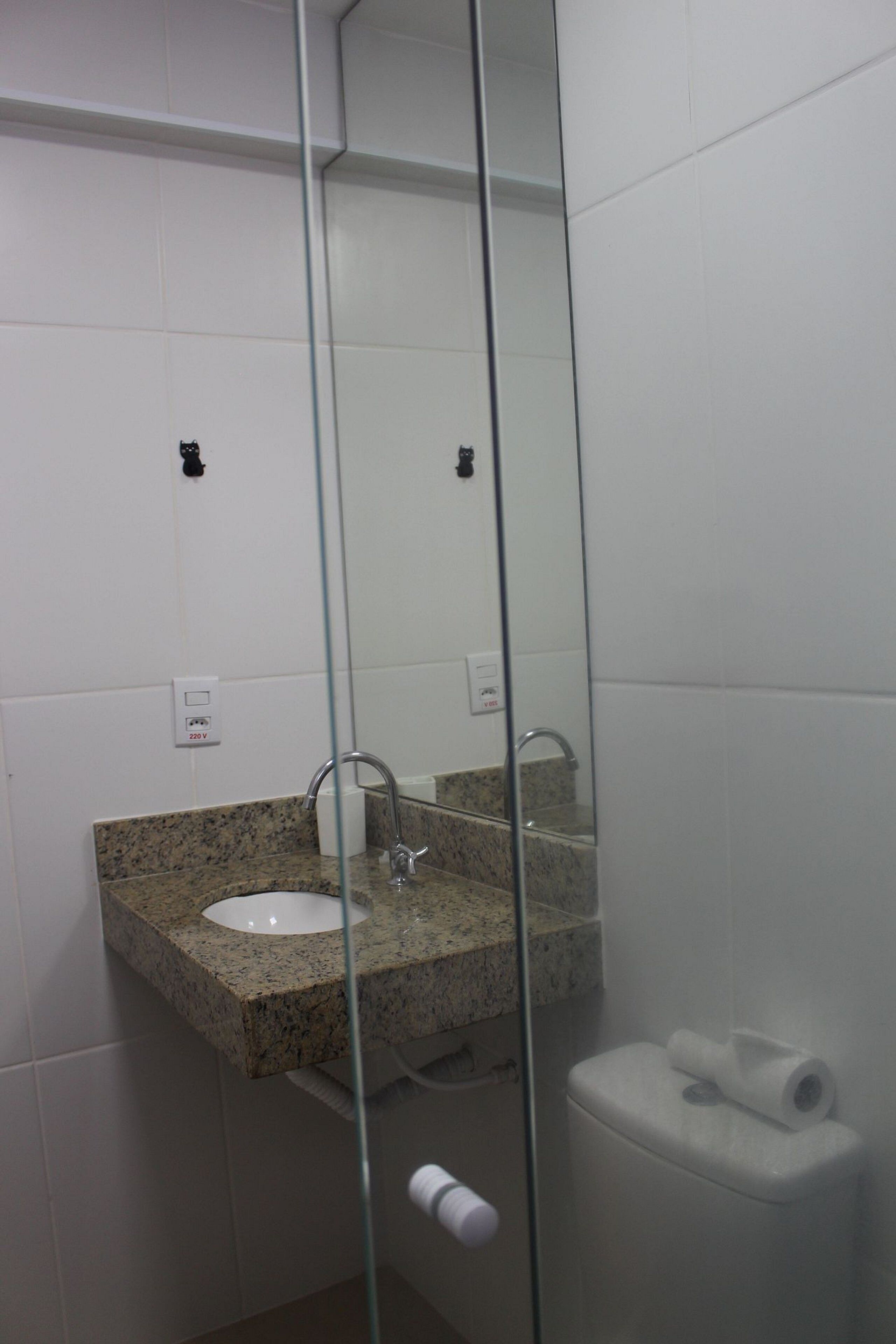 Un baño con lavamanos de encimera de granito, un espejo y un inodoro.