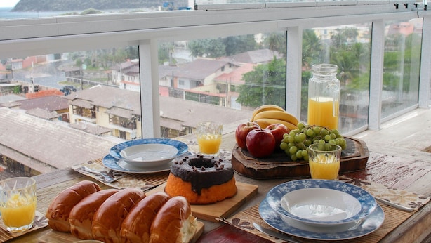 Ett frukostbord med bakverk, frukt och juice, med utsikt över en kuststad.