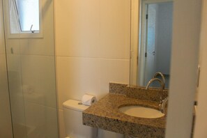Une salle de bain avec un lavabo en granit, des toilettes et une douche.