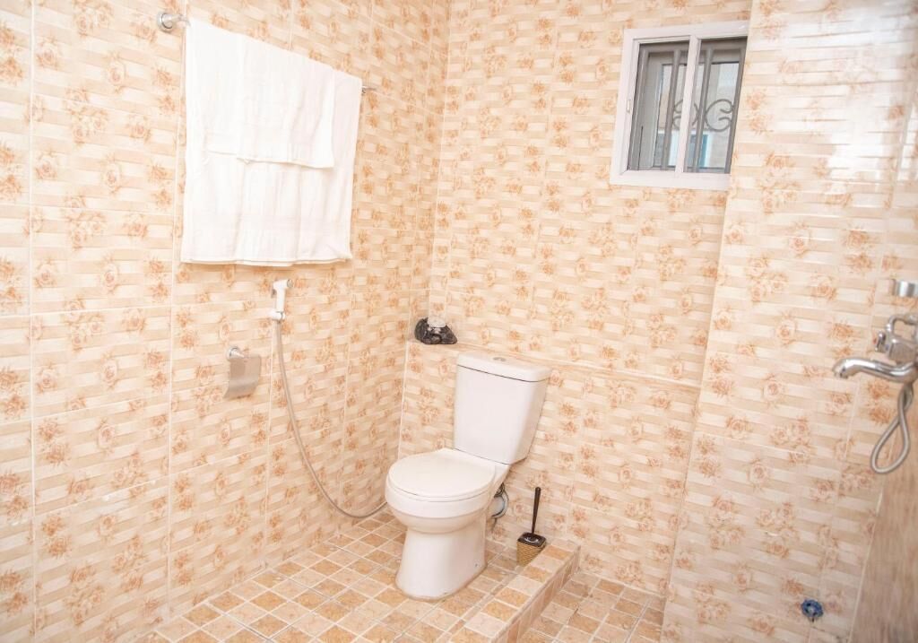 A small bathroom with a toilet, a shower, and a window.