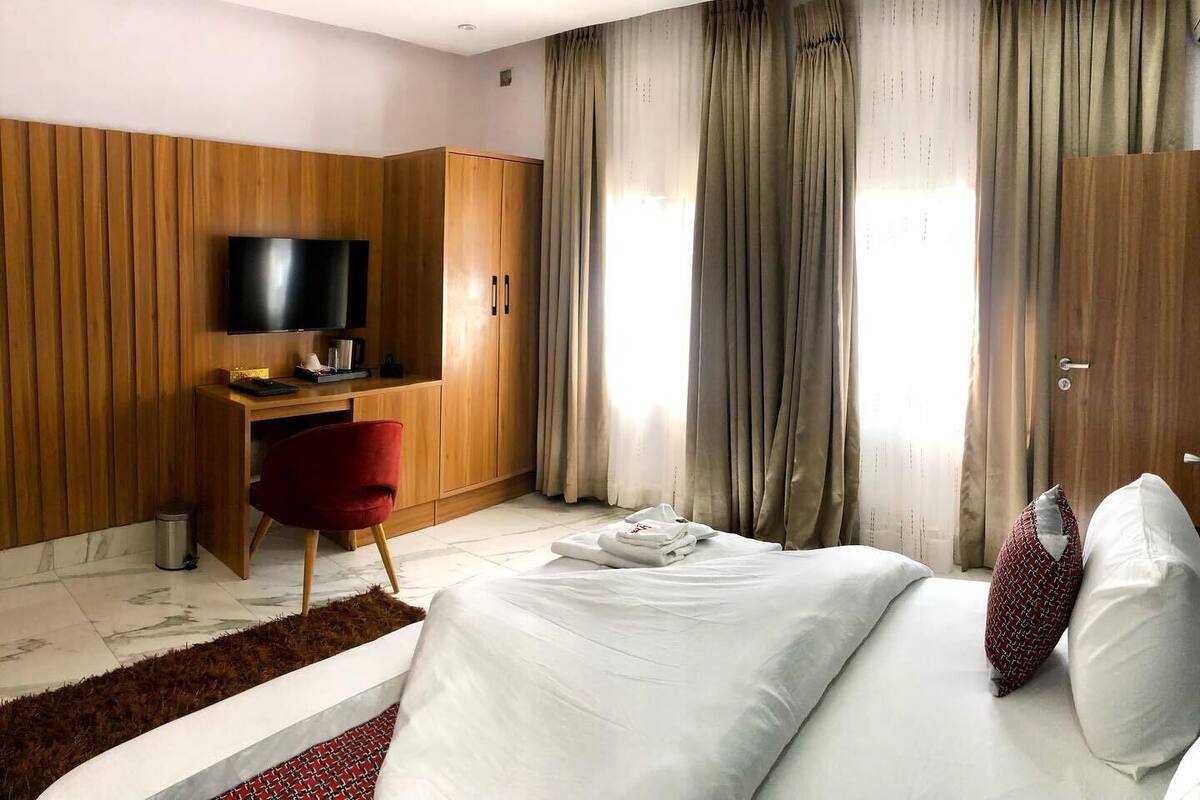 Une chambre d’hôtel avec un lit, un bureau, une télévision et des rideaux.