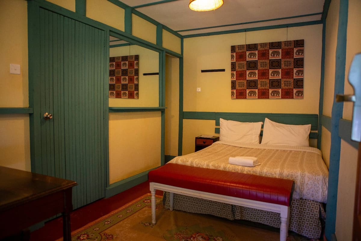 Un dormitorio con una cama, un banco, una mesita de noche y una pared decorada con motivos.