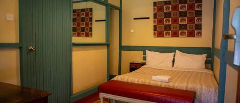 Un dormitorio con una cama, un banco, una mesita de noche y una pared decorada con motivos.