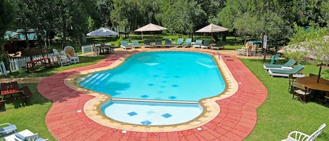 Een buitenzwembad, parasols bij het zwembad en ligstoelen