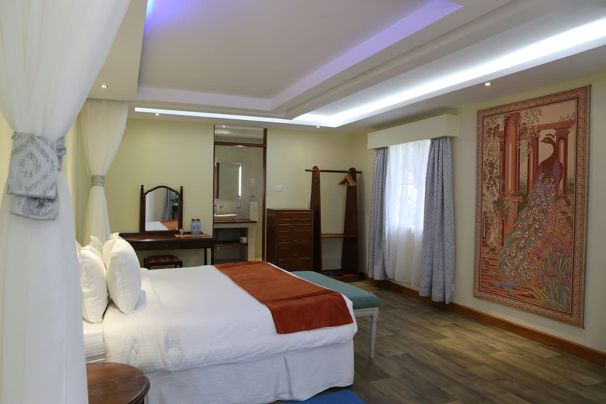 Habitación de hotel con una cama grande, un escritorio con espejo, un armario y un tapiz decorativo de gran tamaño en la pared.