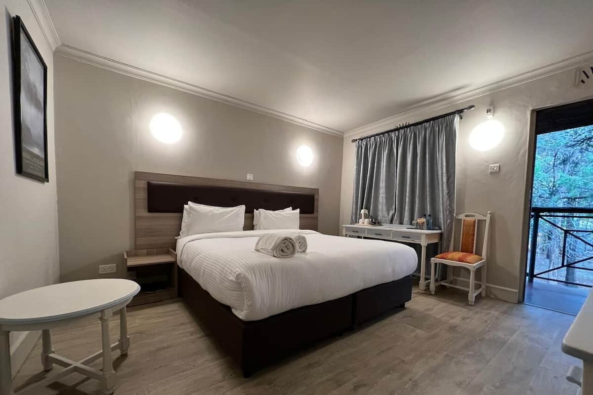 Una habitación de hotel moderna con una cama grande, mesitas de noche, un escritorio pequeño y una silla.