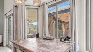 A dining area with a rustic wooden table, a glass-top coffee table, and a view of the outdoors through large sliding glass doors. - Gorgeous backyard views- home gym- pet friendly! (Oro Valley)