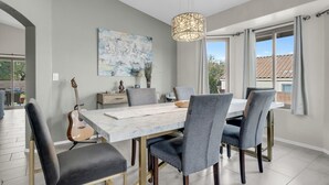 A dining area with a marble table, grey upholstered chairs, and a hanging light fixture. - Gorgeous backyard views- home gym- pet friendly! (Oro Valley)