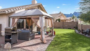 A patio area with a covered seating area, a grill, and a well-maintained lawn. - Gorgeous backyard views- home gym- pet friendly! (Oro Valley)