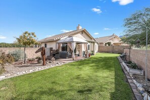 A house with a patio, a covered outdoor seating area, and a well-maintained lawn.