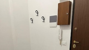 A room with a wooden floor, a door, a cabinet, and wall-mounted hooks. - Saint Rita's (Torino)