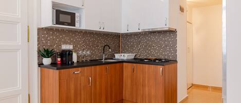 Una cocina moderna con armarios de madera, microondas y salpicadero de azulejos.