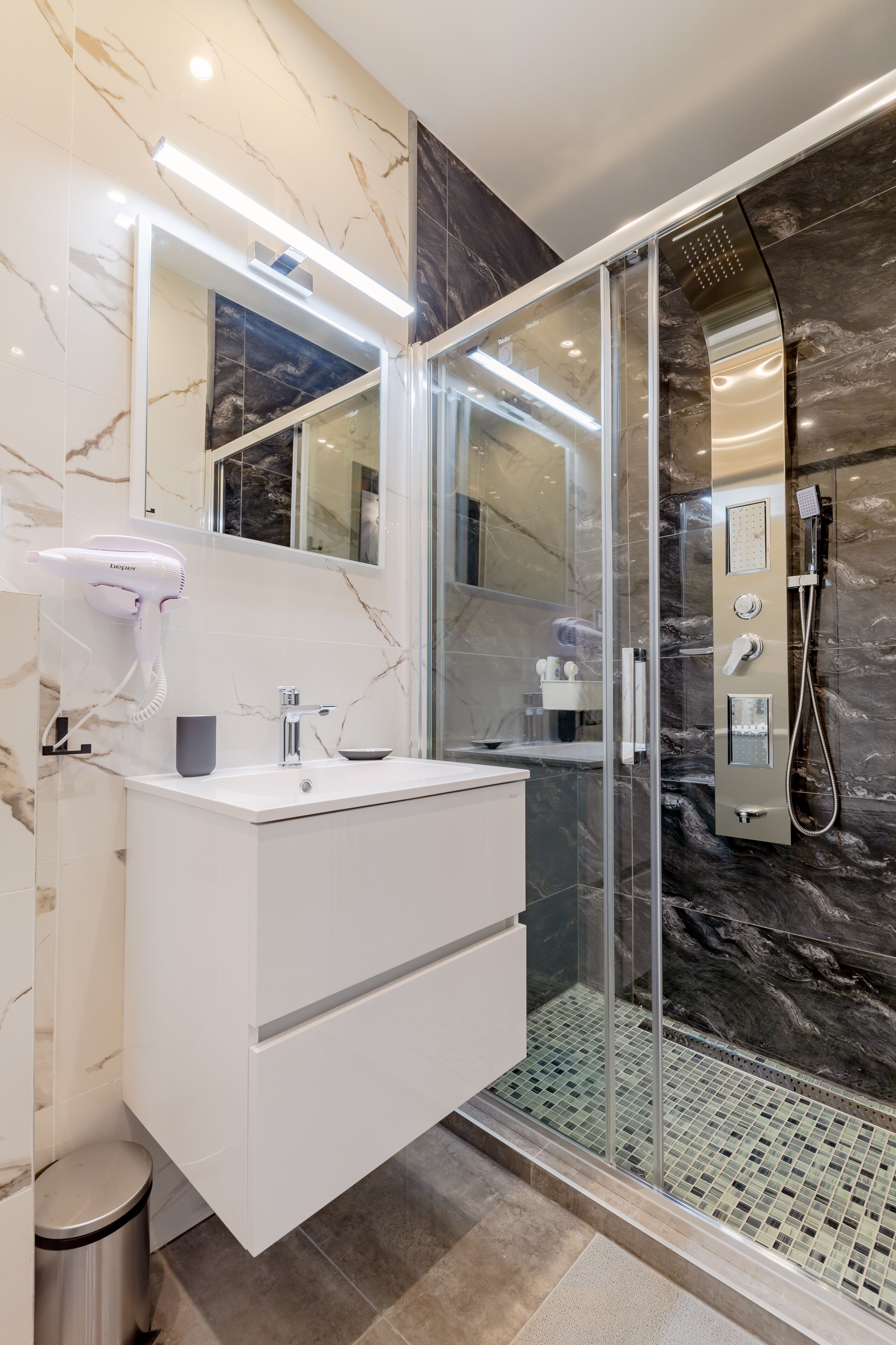 A modern bathroom with a glass-enclosed shower, a white vanity, and a hairdryer.