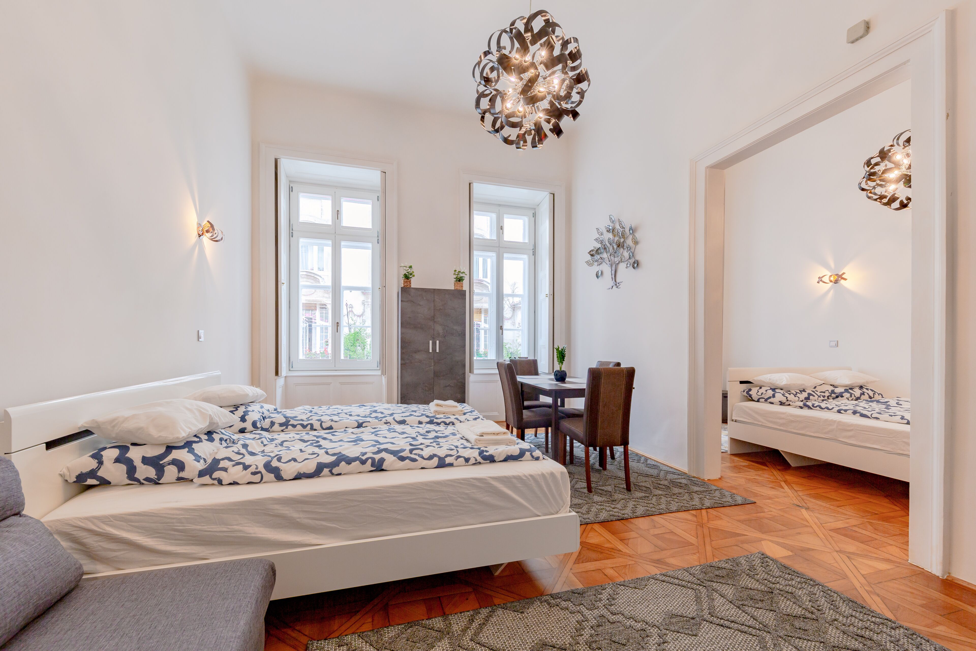 Une chambre moderne avec un lit, un bureau et une chaise. Il y a deux fenêtres et une porte.