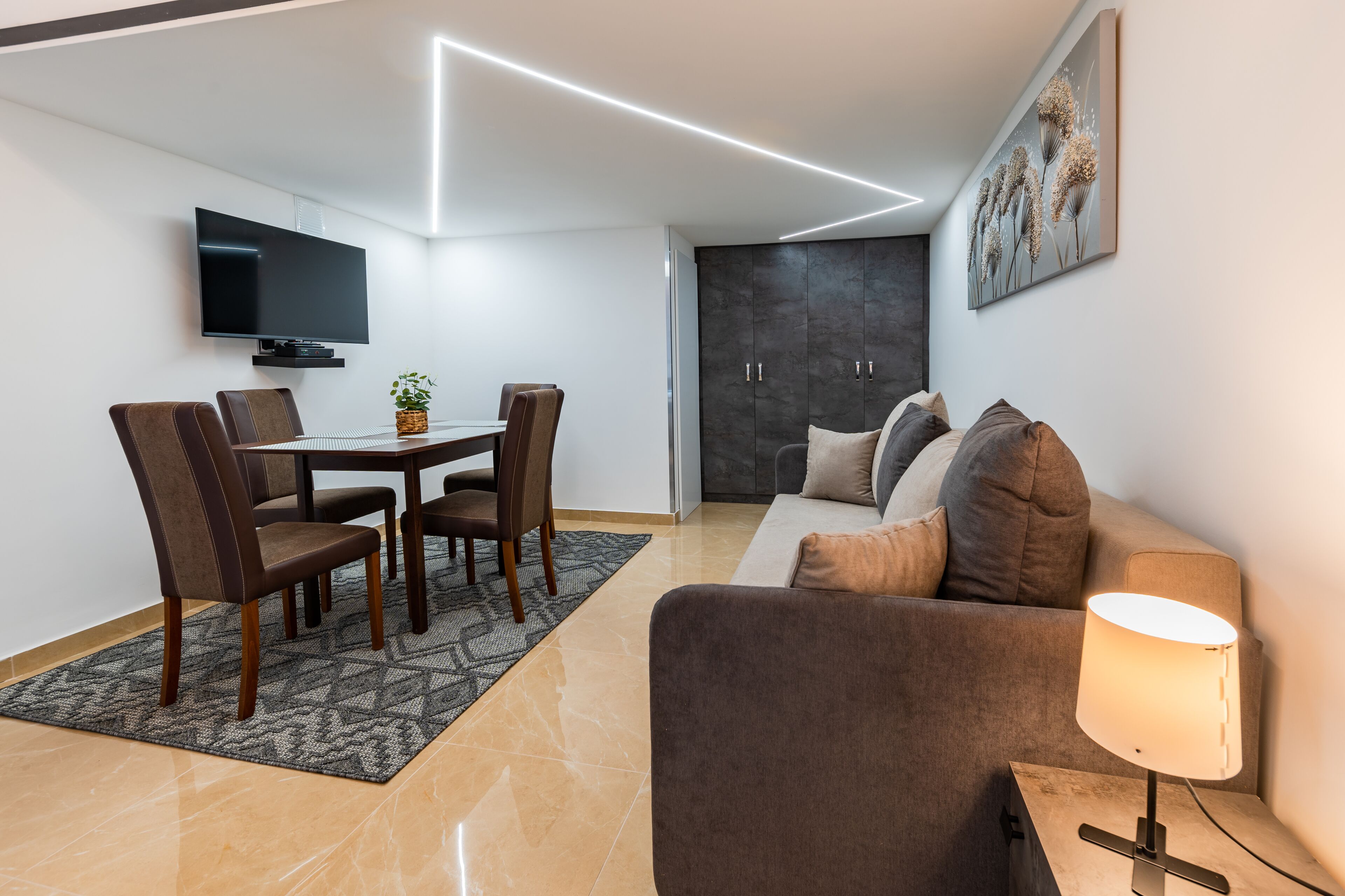 Un salon moderne comprenant un coin repas, un téléviseur à écran plat, un canapé et une lampe.