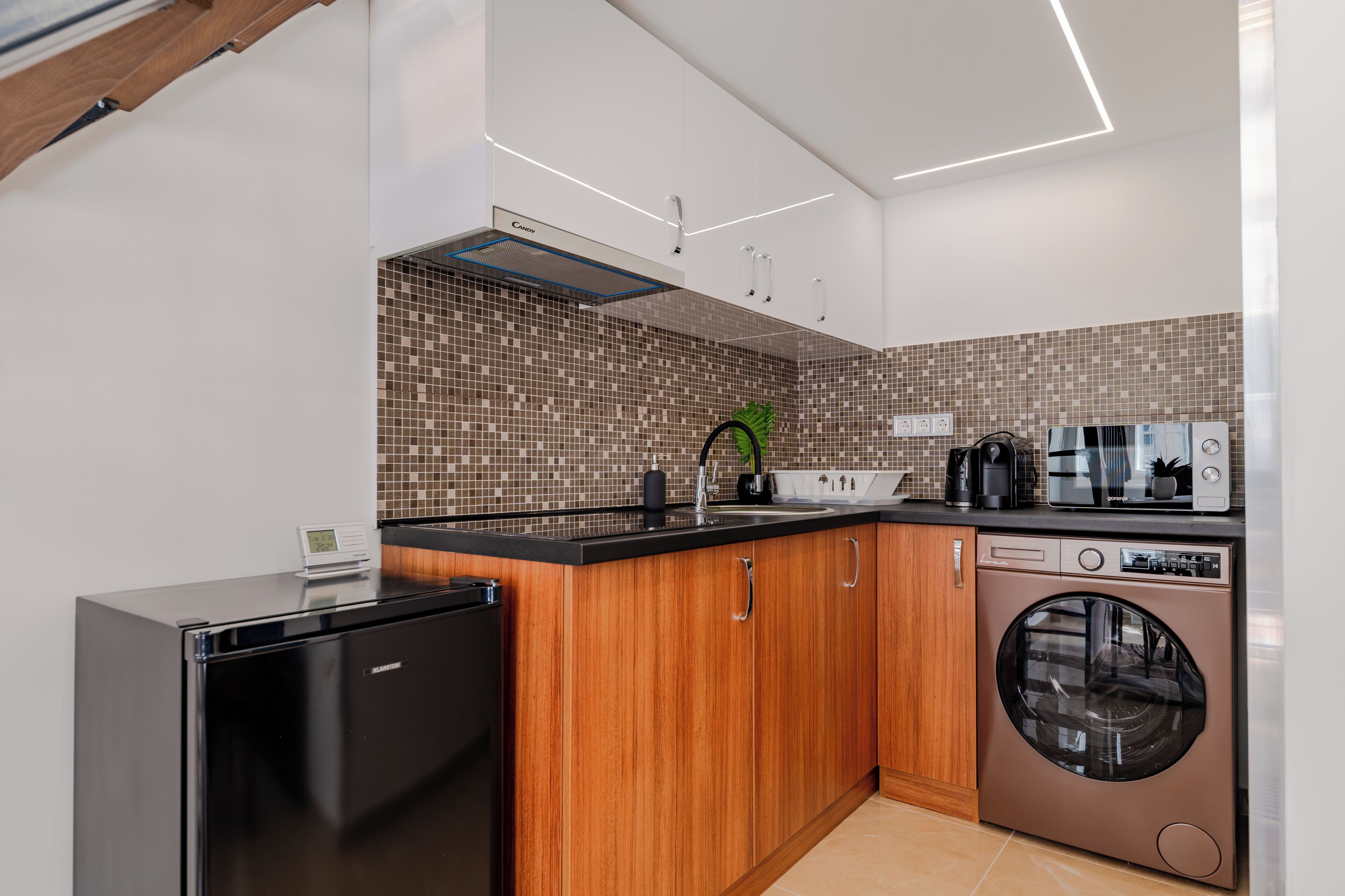 A modern kitchen with a built-in washing machine, a refrigerator, and a microwave.