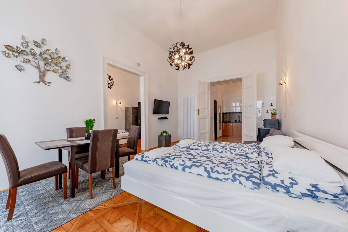 Un dormitorio moderno con una cama grande, un escritorio con silla, un televisor y una araña.