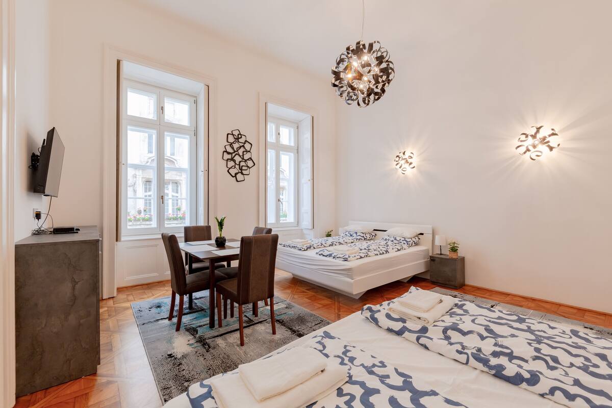 Un dormitorio moderno con cama, mesitas de noche, un escritorio y un rincón comedor.